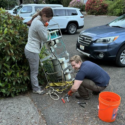 Ella Crotty and Han Weinrich preparing an automated sampler in a hotel parking lot