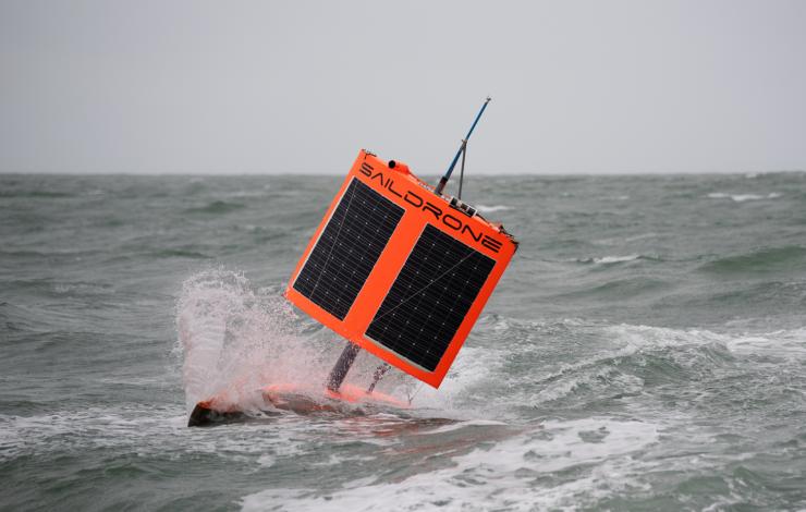 Orange autonomous vehiclewith a square wing in stormy water conditions 