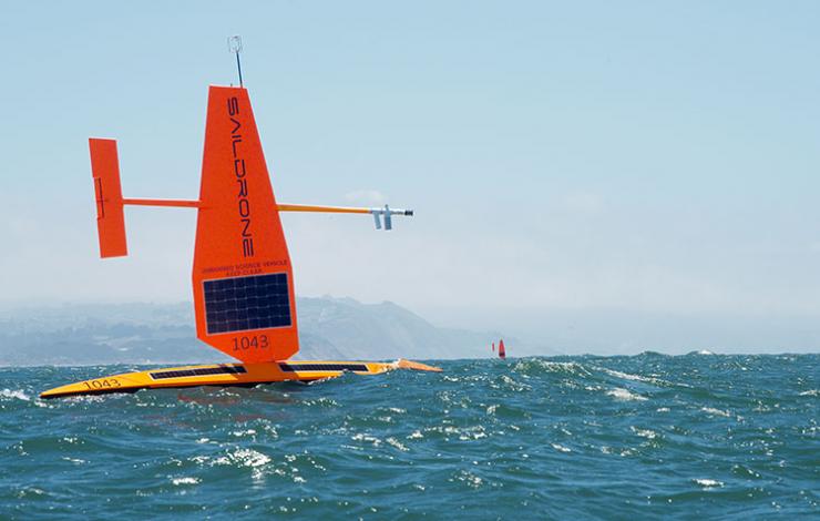 Two orange saildrones in the Pacific Ocean with San Francisco in the background. 